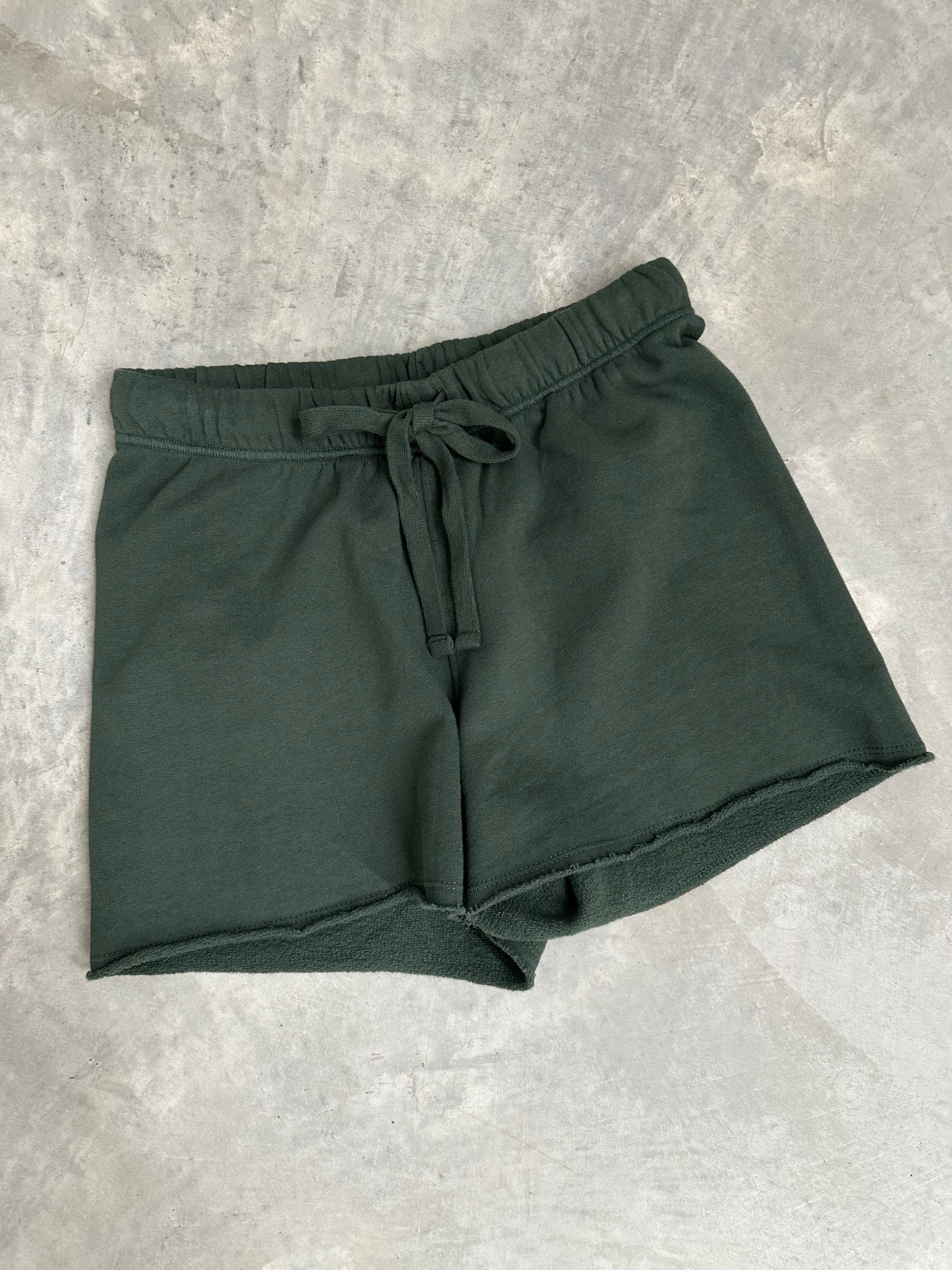 Green shorts with a drawstring on a gray concrete surface