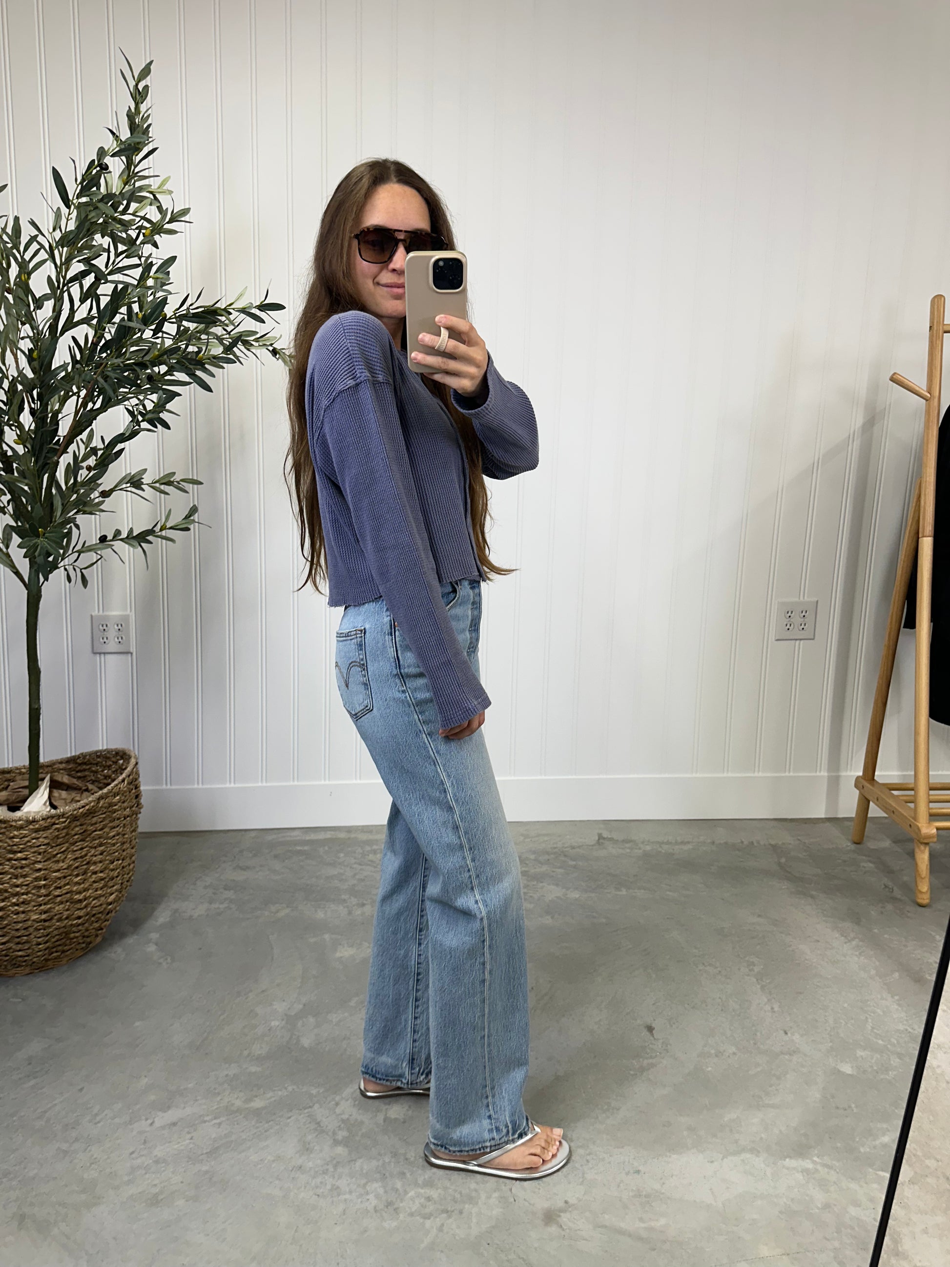 Woman taking a mirror selfie wearing a purple sweater and light blue jeans in a room with a plant and coat rack. Slate Blue Waffle Top